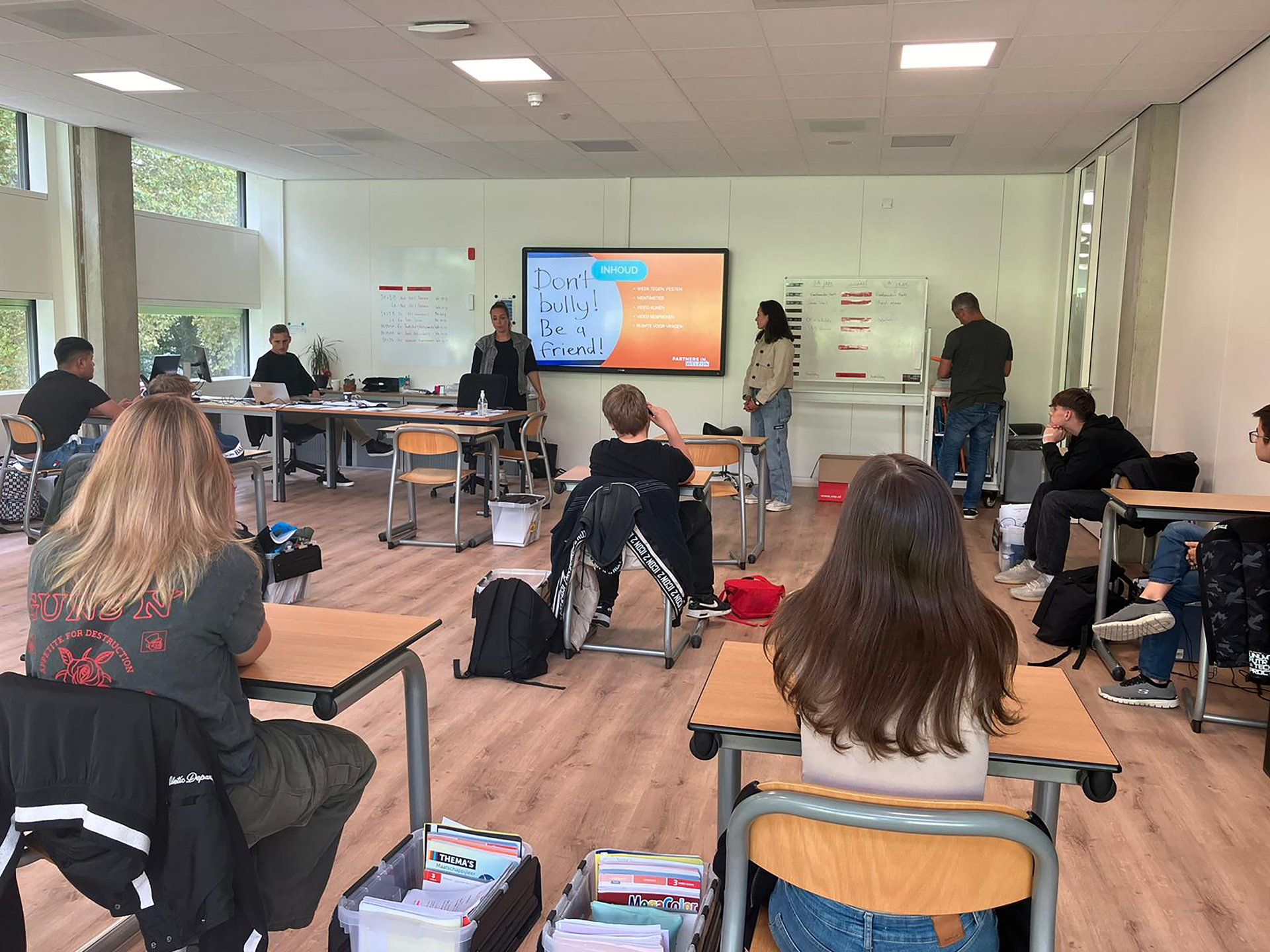 'Don't be a bully! Be a friend!' Dat stoot op een scherm in een klas met scholieren. Schoolmaatschappelijk werk besteedt aandacht aan pesten.